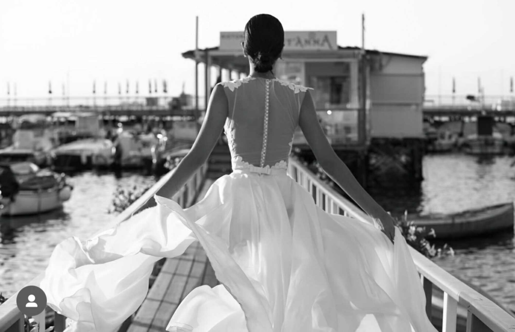 Bride walking along a pier in an elegant wedding gown, photographed in a timeless black-and-white style for a luxury wedding in Dubai.