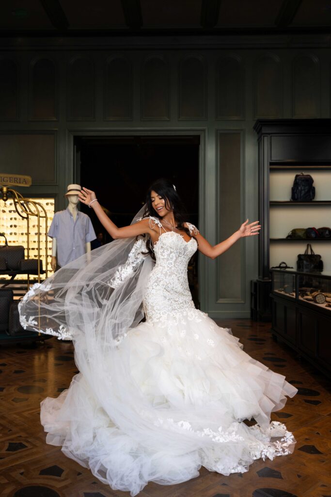 Bride dancing joyfully in a luxury bridal boutique, wearing a lace mermaid wedding gown, captured by French Riviera wedding photographer