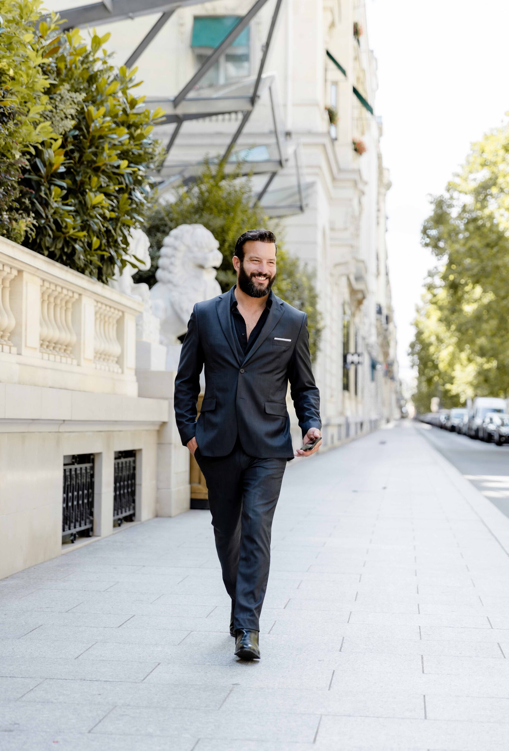 Lillo Vincent, French Riviera wedding photographer and videographer, walking in a black suit on a luxury Parisian street.
