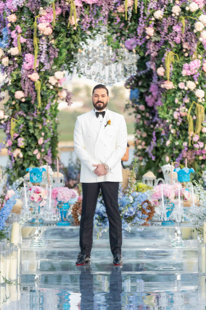 Groom standing under floral archway.